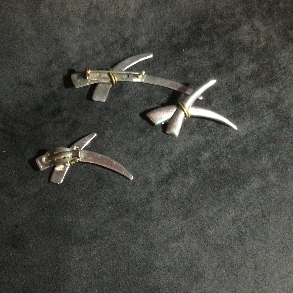 A brooch and a pair of silver colored earrings.